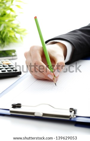 Financial data analyzing. Close-up photo of a businesswoman's hand writing and counting on calculator in office.  Selective focus