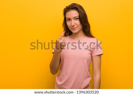 Young european woman isolated over yellow background pointing with finger at you as if inviting come closer.