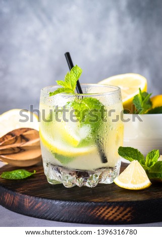 Lemonade. Summer cold drink with lemon, mint and ice on light table.