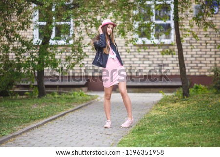 close up portrait of beautiful stylish kid girl in hat near brick building in urban street as background