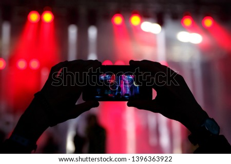 Hands with a smartphone records live music festival, Taking photo of concert stage