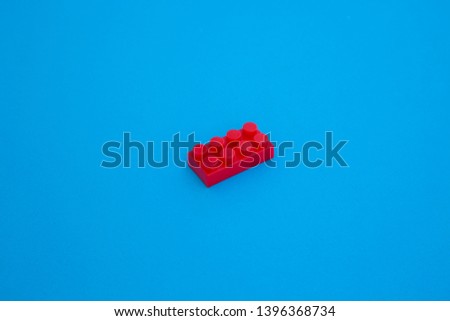 red cubic plastic block on blue paper background . object in the middle and many space for text . isometric business concept .