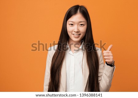 Young business chinese woman smiling and raising thumb up
