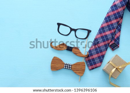 Father's day concept. Hipster glasses, gift box tie and funny moustache over blue wooden background. top view, flat lay