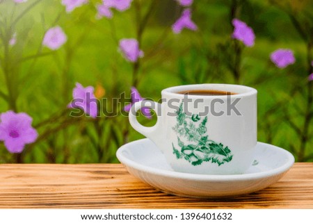 A cup of coffee using vintage  on the wooden table and the plantation background with copy space for your text