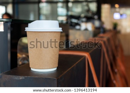 closeup paper cup of hot coffee in cafe with soft-focus and over light in the background