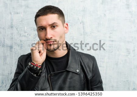 Young rocker man with fingers on lips keeping a secret.