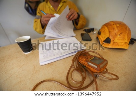 Gas tester atmosphere on defocused isolated miner worker double checking Job Hazard Analysis (JHS) risk assessment on the table when working on confined restricted space 