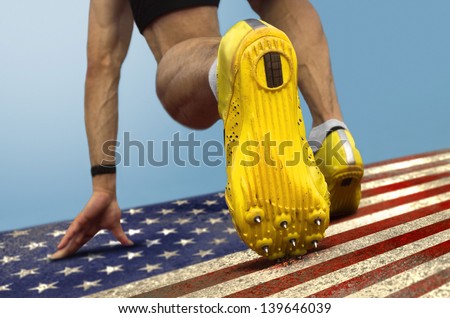 Sprinter with spikes is in start position on grungy US flag