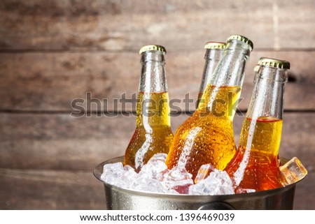 Cold bottles of beer in the bucket on the wooden background Royalty-Free Stock Photo #1396469039