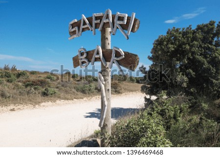 Safari Bar wooden board on the side of a dirt road, summer adventure concept