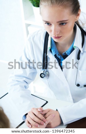 Young Caucasian woman doctor holding female patient's hand for encouragement and empathy. Partnership trust and medical ethics concept.