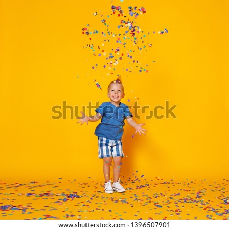 happy birthday child boy with confetti on  colored yellow background
