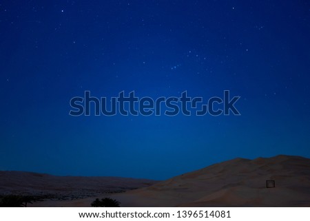 Night sky full of stars over sand dunes in a desert with camps 