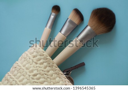 ecological brushes for a make-up from a bamboo and an artificial bristle in a wattled cosmetics bag from rice straw on a blue background