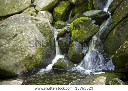 A beautiful waterfall flowing through some rocks in the woods.