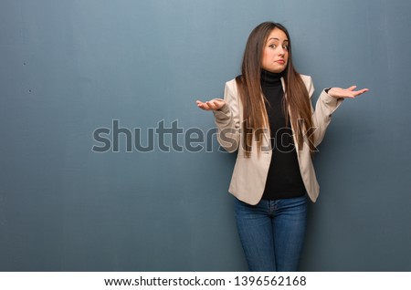 Young business woman doubting and shrugging shoulders Royalty-Free Stock Photo #1396562168