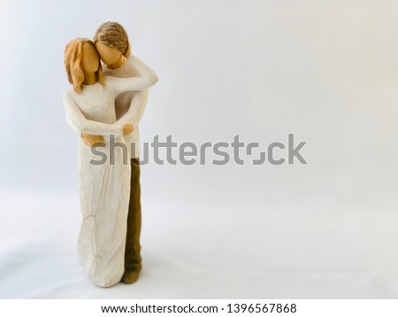 Figures - a couple in love. Figurines - he and she, love forever. Statuette - a guy and a girl hug and kiss. Wooden figures on a white background.