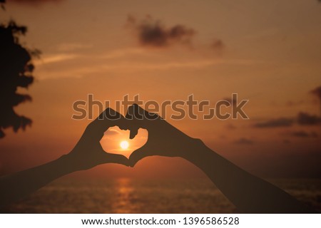 hands in the form of heart against the sky pass sun beams. Hands in shape of love heart