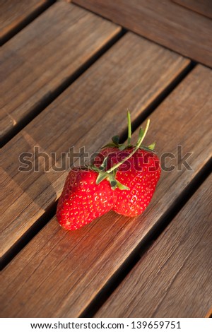 Two fresh strawberries on wooden background.
