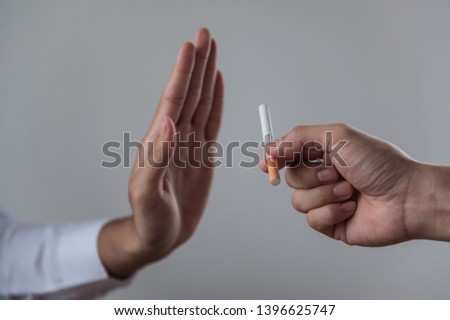 Hand making reject or refuse sign for cigarette from friend. Can use for quit smoking or world no tobacco day concept.