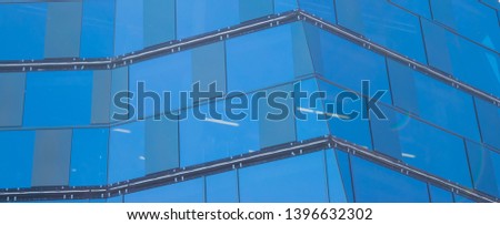 Modern architecture.Glas texture. Fragments of a glass building with a blue mirror facade with the street and square reflected in it.