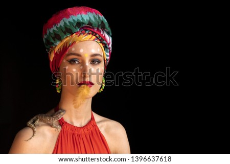 The model poses in the image of an Oriental Princess in a photo Studio on a dark background. model in a bright outfit and red dress. model in a bright outfit and with a lizard on his shoulder. free
