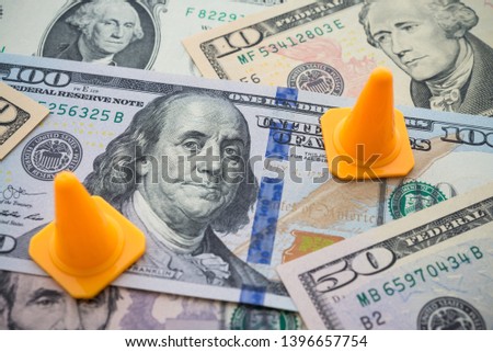 Traffic cone warning area on US dollar banknotes bill background. Concept of fix, repair, USA or global world economy financial crisis solution, personal loan refinance.