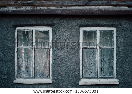 Closeup photo of wall of gray buildnig with vintage windows.