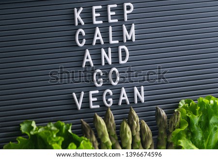 Keep calm and go vegan message on board with asparagus and green salad below. Be Vegan concept