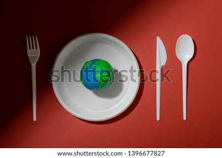 Serving table with Earth planet, plastic plate, spoon, fork and knife. Ecology Concept for Earth Hour, Earth Day, Ocean Day and other ECO dates.