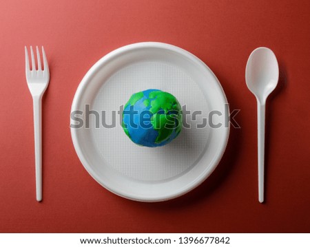 Serving table with Earth planet, plastic plate, spoon and fork. Ecology Concept for Earth Hour, Earth Day, Ocean Day and other ECO dates.