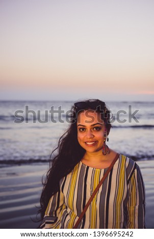 A girl with beautiful eyes at the beach, smiling and giggling.