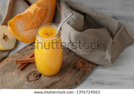 Traditional autumn pumpkin smoothie with apple and cinnamon in glass jar on neutral grey background