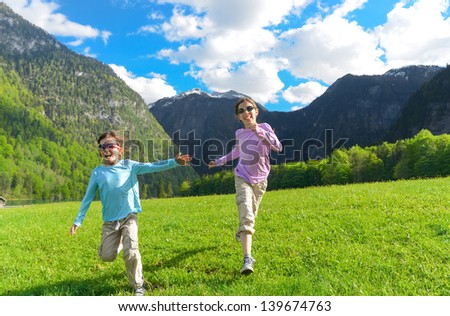 Happy kids having fun and running outdoors, family vacation with children in mountains 