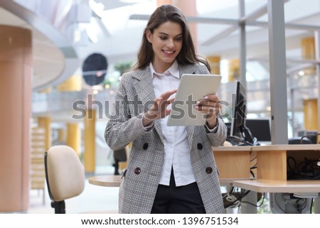 Young smiling businesswoman in office working on digital tablet.
