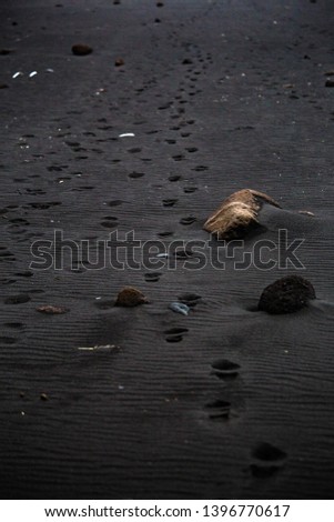 Footprints from shoes in black sand on Reynisfjara Beach in Vik Iceland in autumn