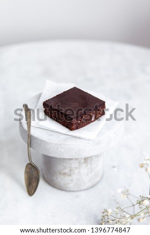 Vegan raw brownies with nuts and dates, on white marble background with copy space. Healthy dessert concept