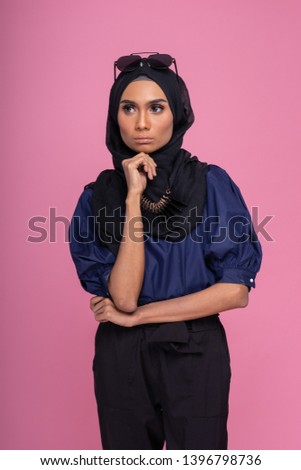 Beautiful Muslim female model wearing three quarter pants and blue shirt with hijab, isolated over pink background. Studio fashion and beauty concept.