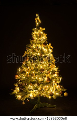 Golden Christmas tree with decorations and lights bokeh in a black background