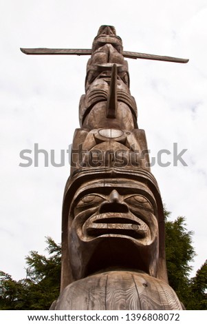 Looking up at a single wood Totem Pole with white sky background at Hallelujah Point in Stanley Park, Vancouver