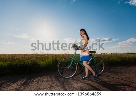 girl in a field on a bicycle holding flowers