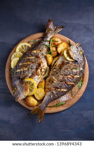 Roasted fish and potatoes, served on wooden tray. overhead, vertical - image