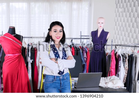 Confident female fashion designer standing with folded arms in the workplace