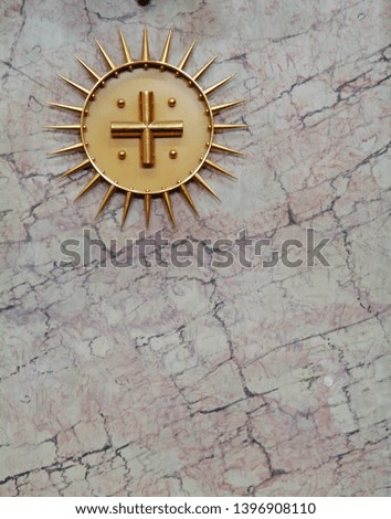 Cross medallion against a marble background in a Ljubljana, Slovenia church
