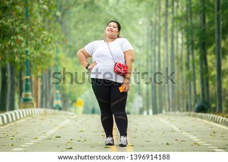 Picture of fat woman looks confident while standing on the road