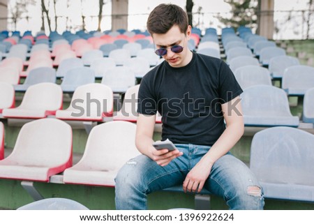 A stylish man in a black T-shirt uses his smartphone