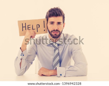 Desperate and frustrated caucasian young businessman holding message asking for help feeling exhausted distressed and sad in Unemployment, Depression, Stress at work place and overwork concept.