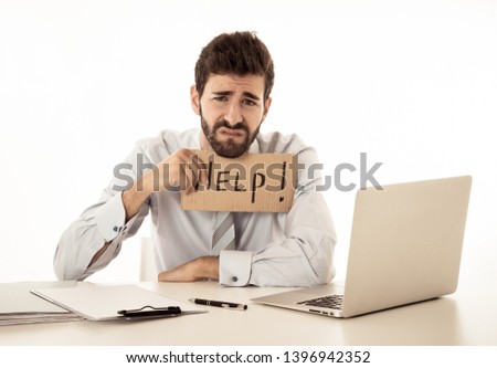 Desperate caucasian businessman with laptop computer suffering stress at workplace holding sign asking for help looking sad angry and overworked. In People Business Overwork and Deadline Pressure.