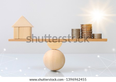 Wooden plank balancing of wood home and coins money comparison of income control expense with light effect graphic. Property investment and house mortgage. Financial real estate business concept